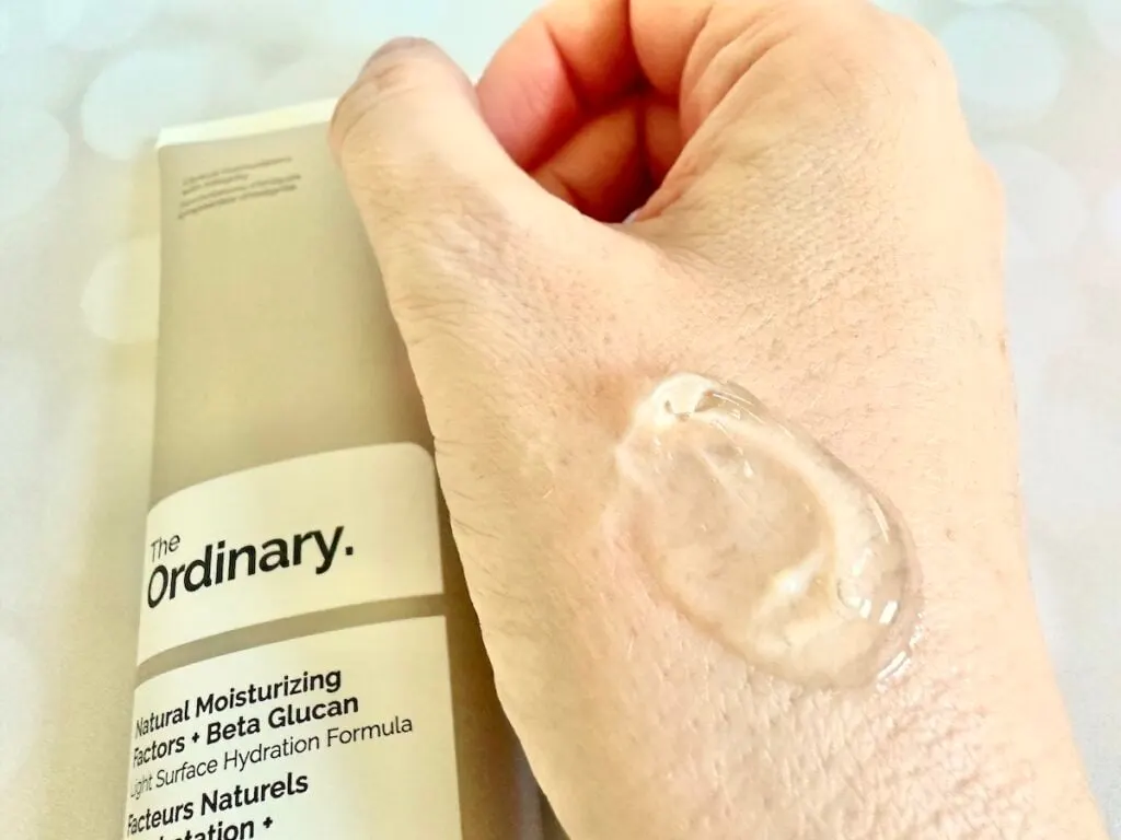 The Ordinary Natural Moisturizing Factors + Beta-Glucan, flatlay of tube next to sample on hand.