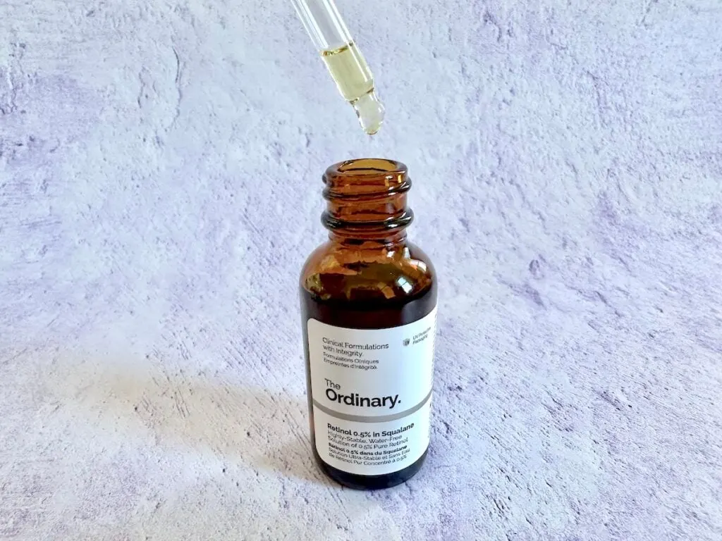 The Ordinary Retinol 0.5% In Squalane open with dropper on purple background.