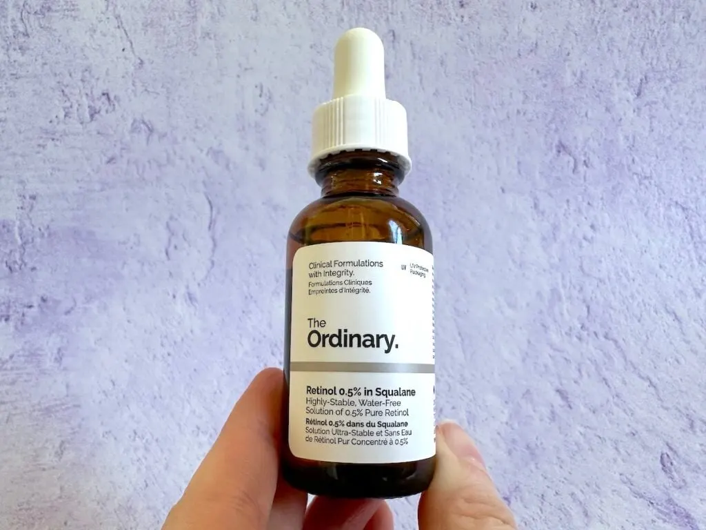 The Ordinary Retinol 0.5% In Squalane, handheld in front of purple background.