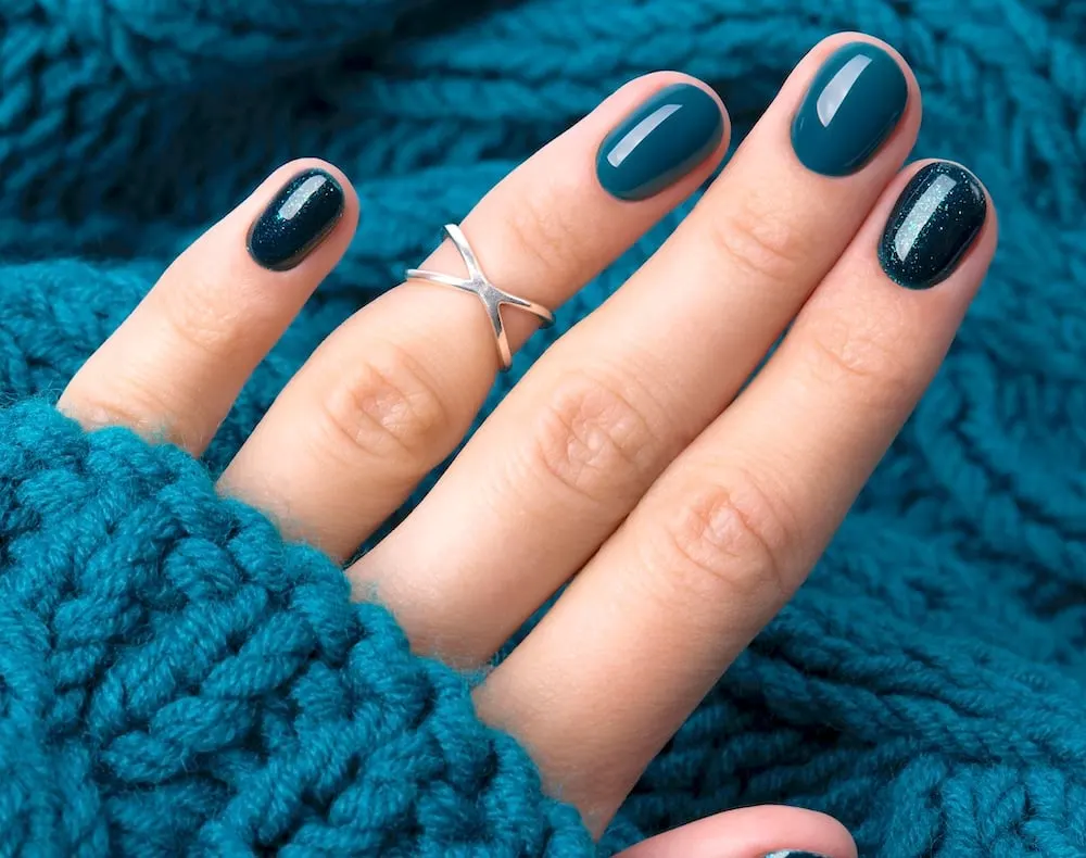 Teal blue winter nails surrounded by teal sweater.