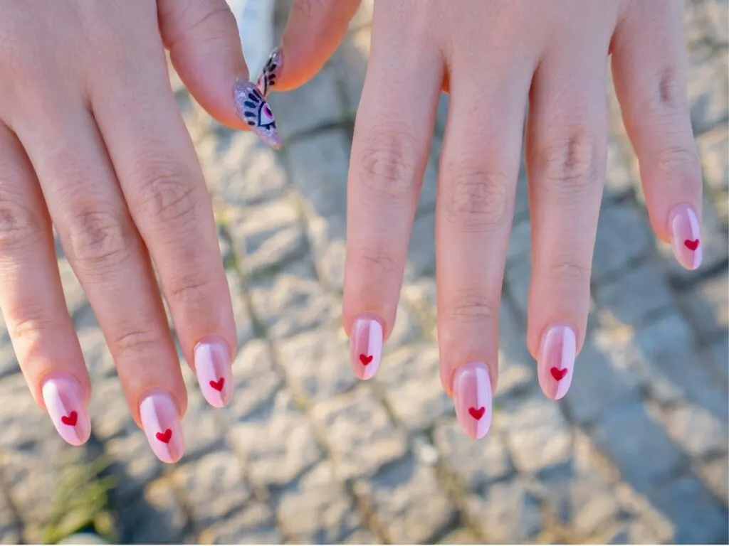 This image showcases a close-up view of a person's hands, revealing a charming nail art design perfect for Valentine's Day.