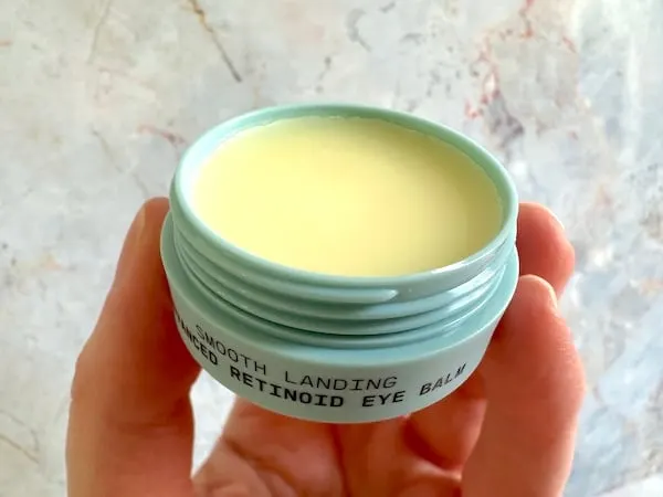 Versed Smooth Landing Advanced Retinoid Eye Balm, open jar, handheld.