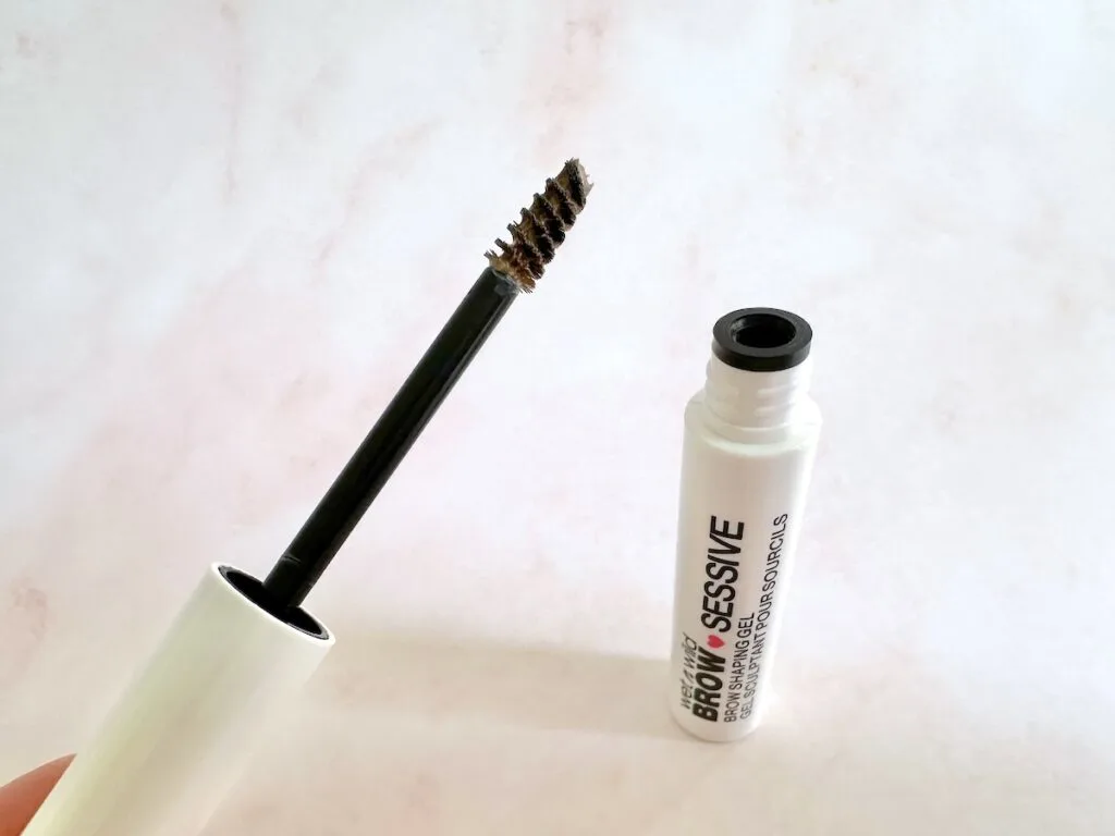 Wet N Wild Brow-Sessive Brow Shaping Gel in the shade Blonde, open tube with applicator wand, handheld.