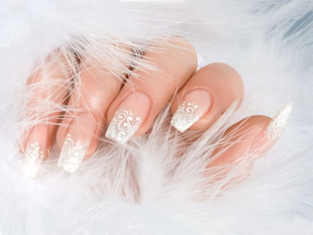 Lace white French tips winter manicure surrounded by soft plush feathers.